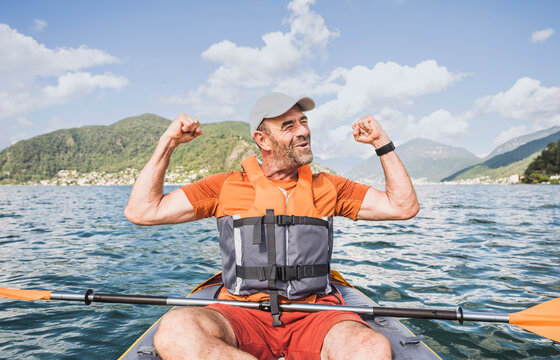 Excited man with arms raised sitting in kayak