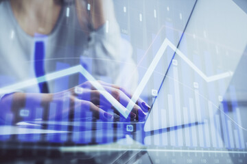 Double exposure of woman hands typing on computer and financial graph hologram drawing. Stock market analysis concept.