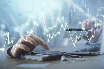 Double exposure of man hands holding a credit card and Forex graph drawing. Stock trading and digital fintech in Internet E-commerce concept.