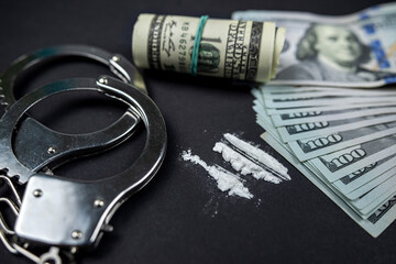 small bags of drugs and US dollar bills with handcuffs and bullets from a gun.