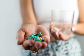 woman takes cosmetic supplements for glowing skin while holding fish oil capsules and glass