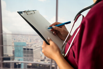 female nurse in uniform writing prescription on clipboard filling  history while standing