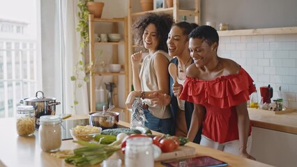 Beautiful young women spending time together and having fun. Latin and hispanic girls lifestyle moments in the kitchen while cooking. Representation of happy friends laughing and sharing good vibes - Powered by Adobe