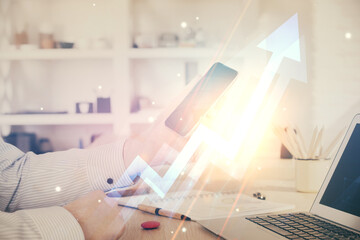 Double exposure of man's hands holding and using a digital device and arrows hologram drawing. Success concept.