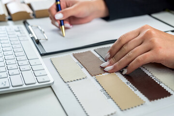 wood laminate flooring for furniture design and male hands choosing a model at an office desk.