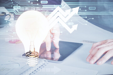 Double exposure of man's hands holding and using a digital device and bulb hologram drawing. Idea concept.