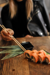 asian food-sushi, chopsticks and knife. woman in black suit.