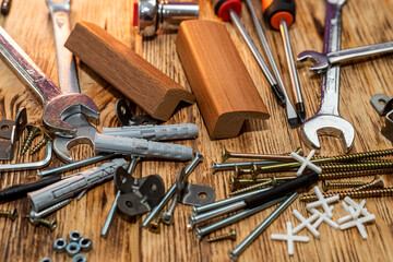 Screws and dowels for hanging objects shown on isolated wood background.