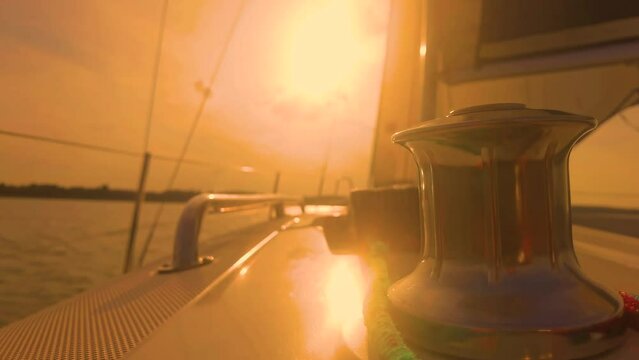Sail boat with set up sails gliding in open sea at sunset