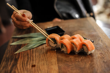 sushi with salmon, chopsticks and vegetables on a wooden board