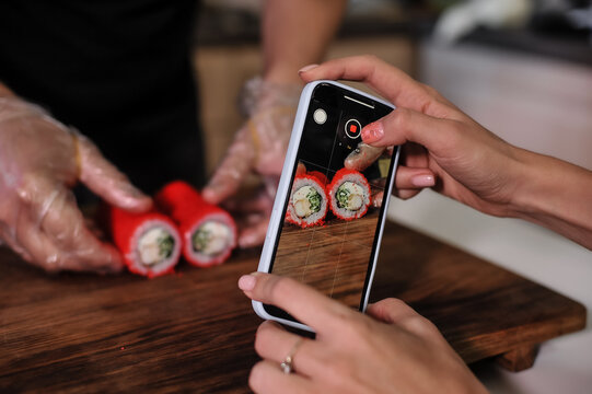 close up of a woman taking a picture of a sushi