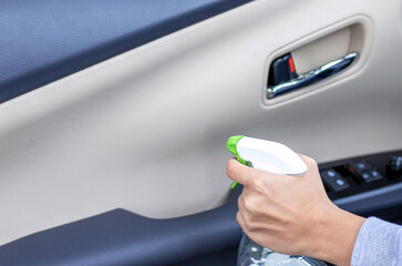 car wash and interior chemical cleaning concept.woman hand use microfiber cloth and spray to clean lateral door from inside,retractable rear view mirror,steering wheel.modern hybrid vehicle clean home