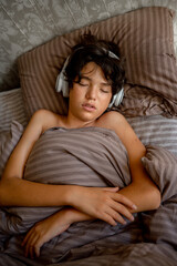 Obraz premium teenage boy sleeps at home on the couch listening to music with headphones