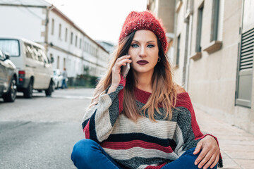 urban young woman in winter clothes on the street talking on the smartphone