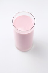 Strawberry flavored pink milk in a glass on a white background.