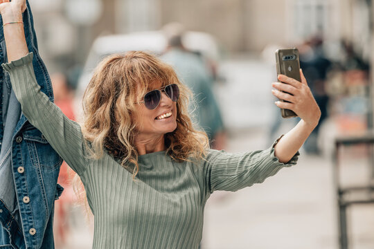 happy woman in the street taking a selfie or live video with the mobile phone