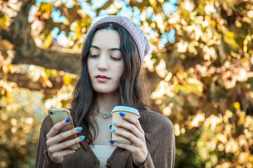 young girl with phone and takeaway in autumn