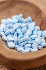 Fototapeta na wymiar Blue round headache painkiller pills in a wooden container