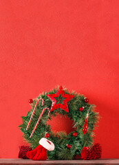 christmas wreath decor with star,bauble,and candy cane,on copy space red wall on wood table