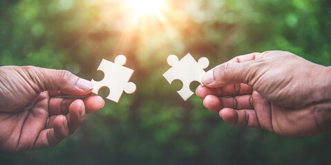 Hands holding jigsaw puzzles on green bokeh nature backgounds, Business matching concept.
