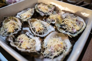Fresh oysters with grated cheese and onion vinaigrette ready to be baked in the oven