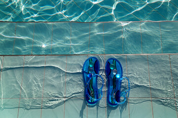 female blue flip-flops left on the stairs leading to swimming pool 