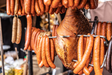 Cured meat products such as ham, sausages and frankfurters hanging at the market vendor booth...