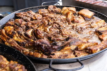 Meat stew with beef, pork and lamb in a juicy sauce bubbling in a large pan in the street market