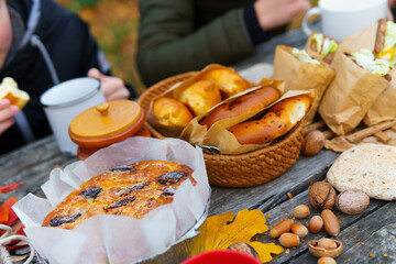 picnic in the autumn season, food on a wooden table, hot tea, pastries and sandwiches