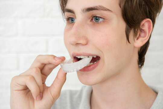 Teen boy holding an silicone aligner braces against white studio background. Dental healthcare concept