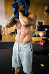 Vertical photo of a man in a gym drying himself with a towel