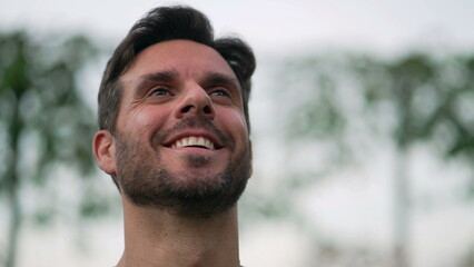 Fototapeta premium Spiritual man closing eyes in contemplation outdoors. Carefree person opening eye looking up at sky smiling with HOPE and FAITH. Grateful emotion