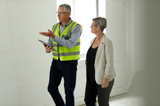 Professional senior engineer builder showing clients around in the new development building