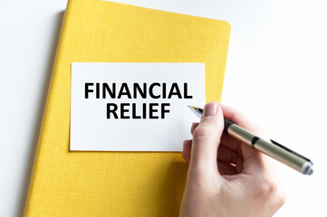 FINANCIAL RELIEF text on a card on a table against a notebook background on a light background