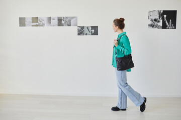 Minimal full length portrait of young woman visiting photo gallery and enjoying art, copy space