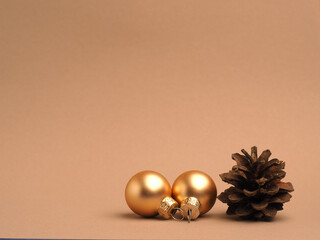 Golden Christmas baubles with a pine cone on a beige background