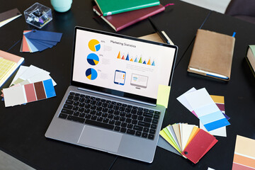 Above angle of laptop with financial information on screen standing on workplace of designer or...