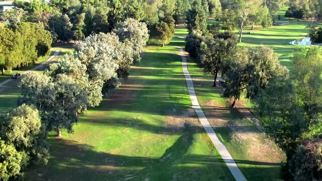Griffith Park Golf Course, Los Angeles CA, Aerial of Green Grass, Trees and Walking Path on Sunny Evening, Dolly Drone Shot