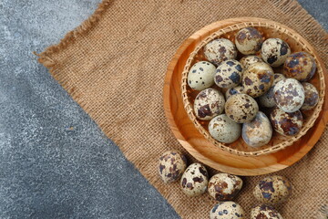 quail eggs in wooden bowl on dark background 