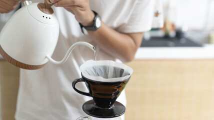 Barista is making drip brewing, filtered coffee, or pour over coffee with hot water and filter...