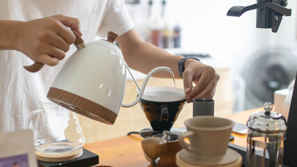 Barista is making drip brewing, filtered coffee, or pour over coffee with hot water and filter...