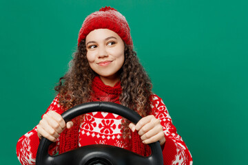Merry young woman in red warm cozy knitted sweater hat posing hold steering wheel driving car look...