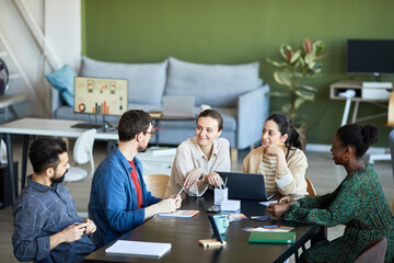 Young colleagues listening to confident businessman explaining his viewpoint or idea for new project at working meeting