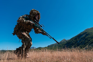 army soldier holding a sniper rifle with scope and walking in the forest. war, army, technology and...