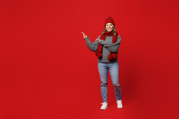 Fototapeta na wymiar Full body young woman wear grey sweater scarf hat point index finer aside on workspace area isolated on plain red background studio. Healthy lifestyle ill sick disease treatment cold season concept.