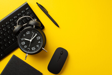Black friday concept. Top view photo of black alarm clock notepad pen computer mouse and keyboard on isolated yellow background