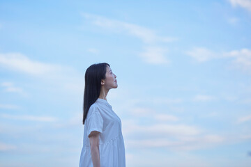 夕暮れ時の青空と白いワンピースを着た女性