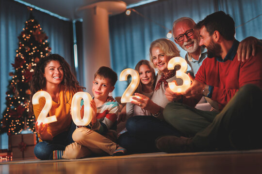 Family celebrating New Year, holding sparklers and illuminative numbers 2023