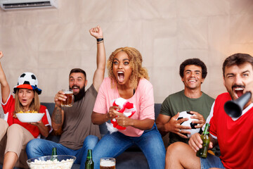 Football fans watching the game on TV, celebrating after their team scoring a goal