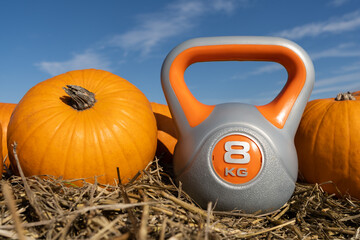 Heavy kettlebell and orange pumpkins on the hay. Healthy fitness lifestyle autumn fall composition...